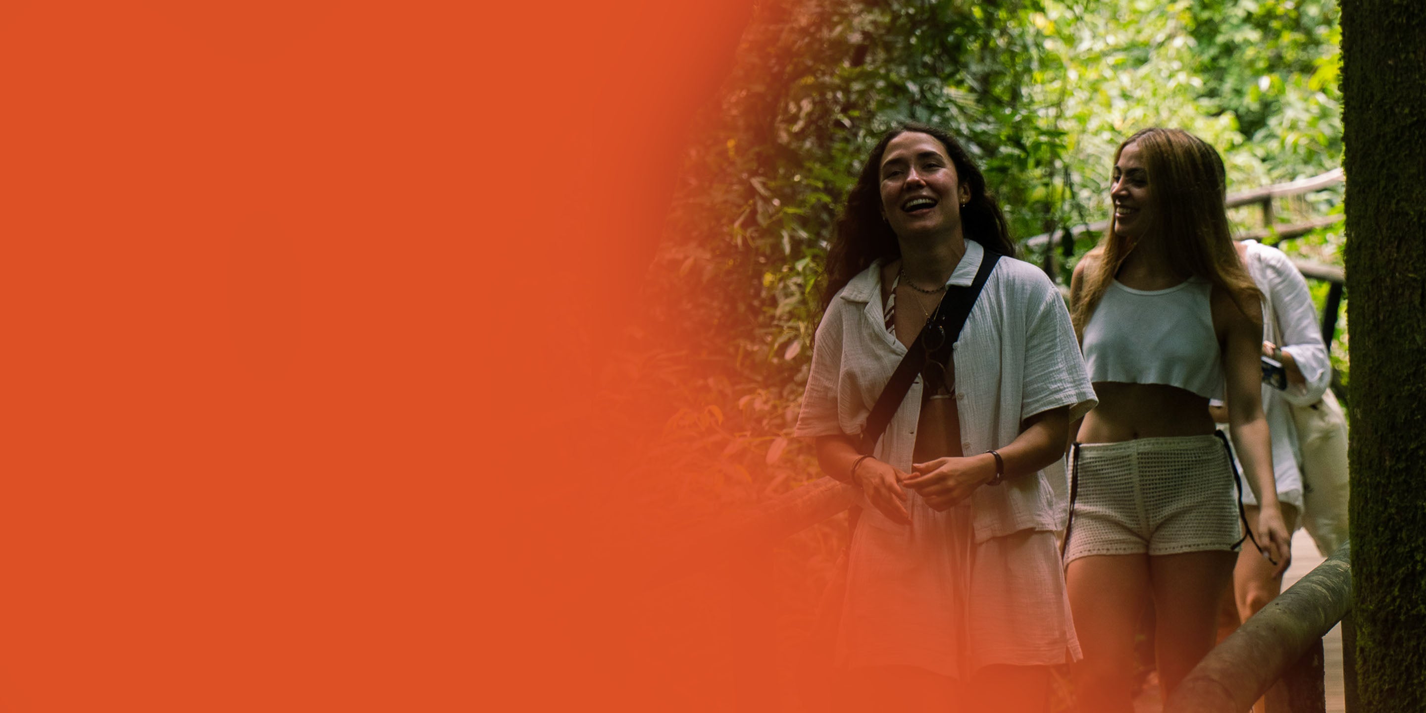 Two people walking through a forest with an orange overlay on the left side.